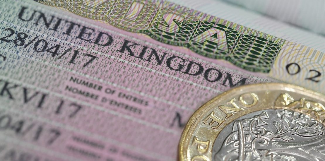 A closeup of a UK visa with a pound next to it