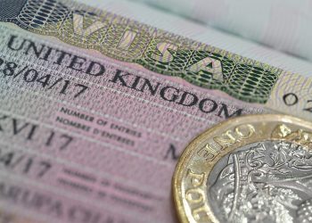 A closeup of a UK visa with a pound next to it